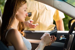 woman getting out her license to show a police officer during a traffic stop