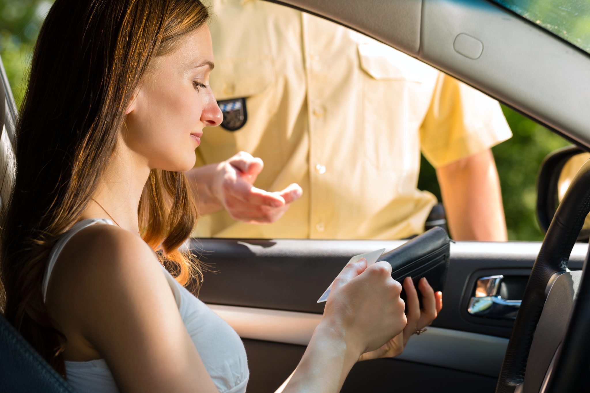 woman getting out her license to show a police officer during a traffic stop