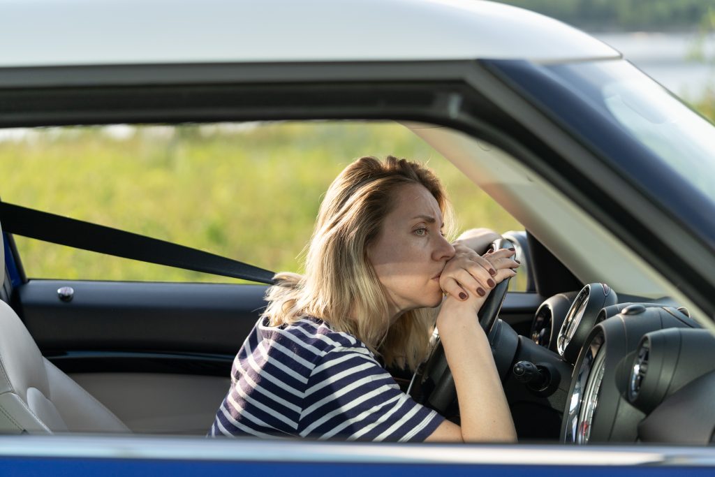 Anxious upset woman in car. Female driver look on road suffer from anxiety headache scared to drive