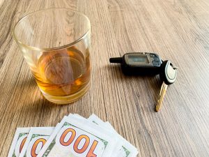 Drunk driving concept. Glass with whiskey and car key on the table.